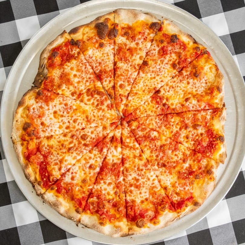 A freshly baked cheese pizza, sliced into many pieces, on a metal tray over a checkered tablecloth.