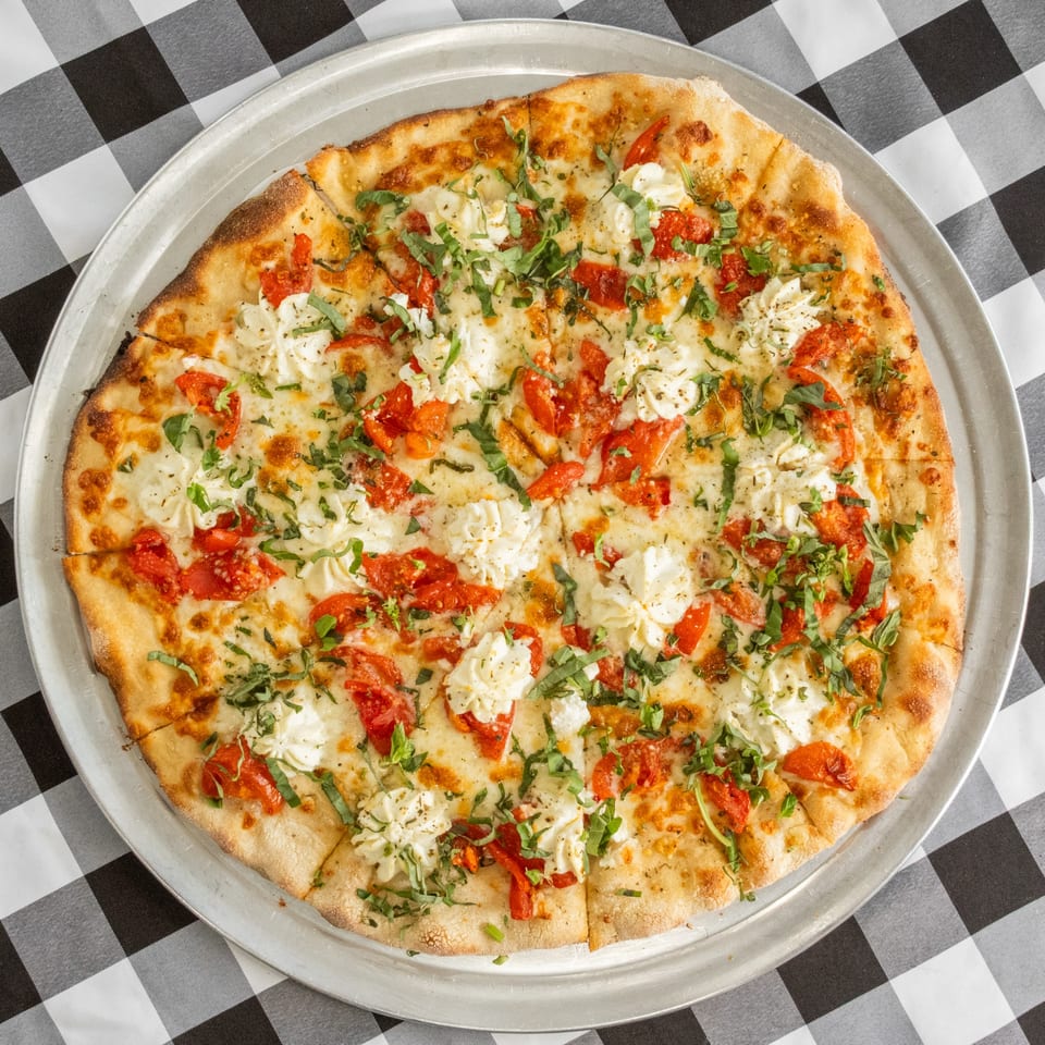 Cafe A Pizza's white pizza with tomatoes, ricotta cheese, and fresh basil on a checkered tablecloth.